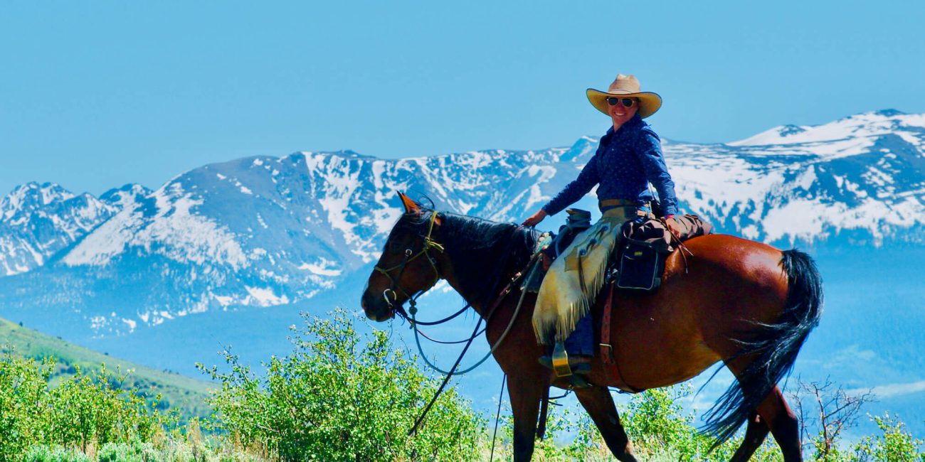 Horseback rider pausing to admire the expansive Colorado mountain views at Rusty Spurr Ranch.