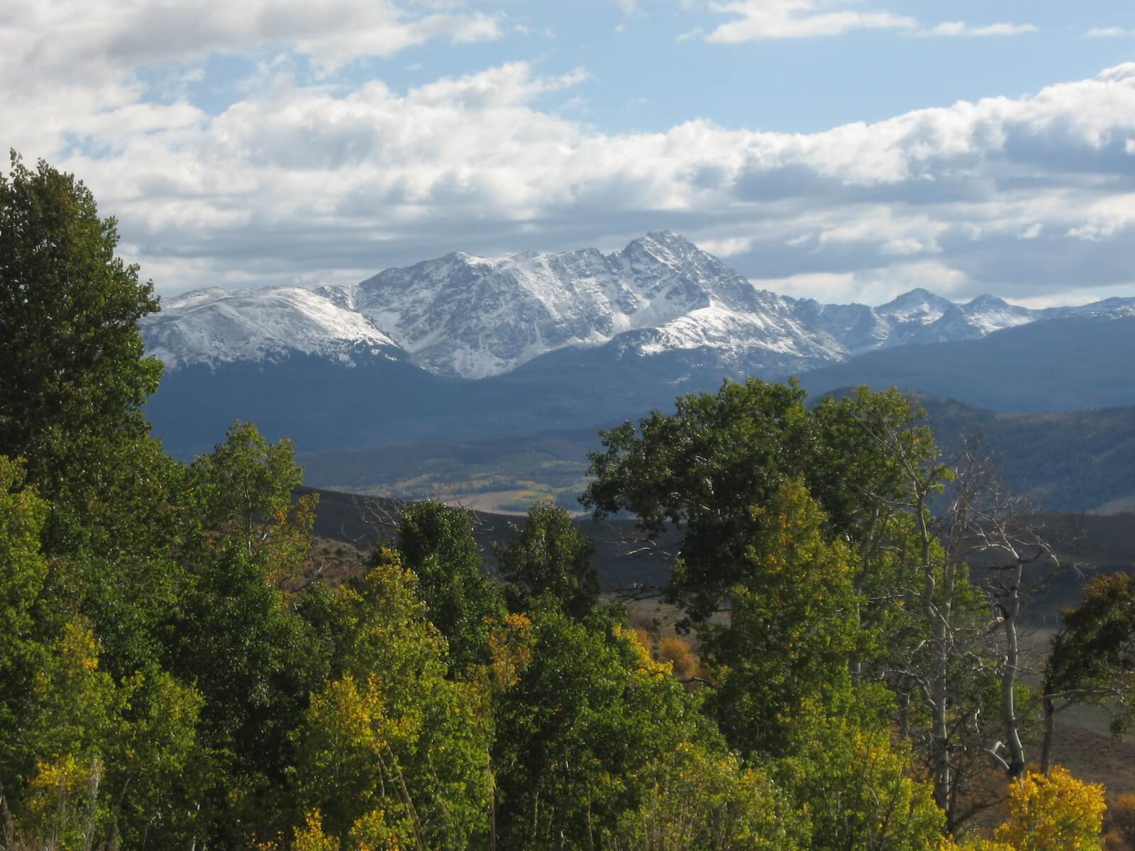 Scenic view of rolling hills and mountain ranges from a horseback riding trail at Rusty Spurr Ranch in Colorado.